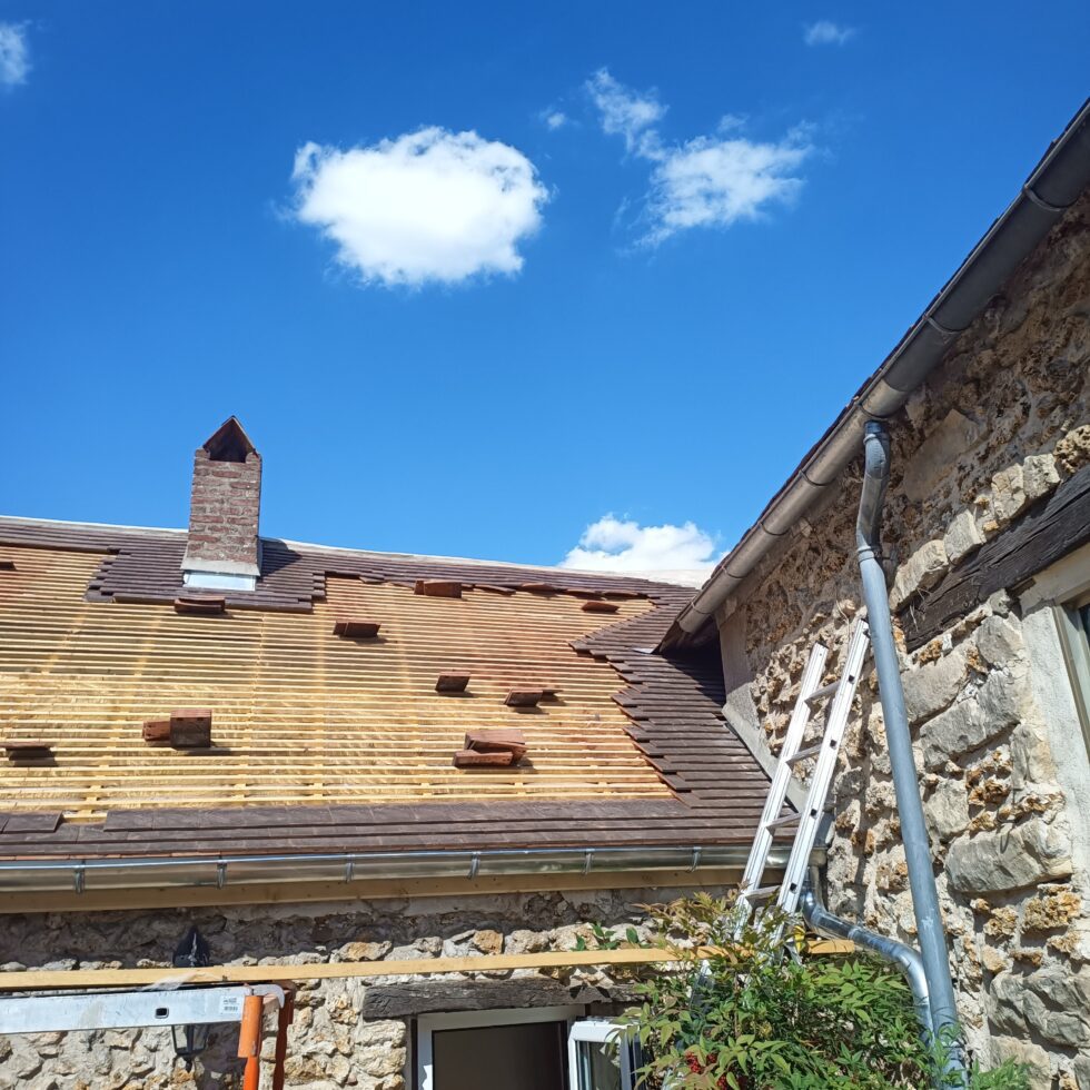 Début de la pose des tuiles durant la restauration complète de la couverture d'une maison ancienne